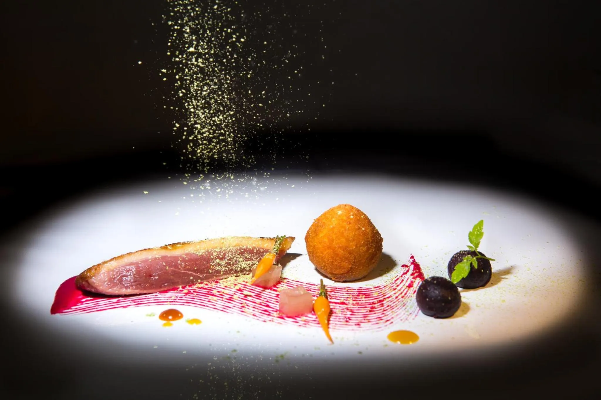 Assiette gastronomique avec une présentation artistique de viande, de fruits et de sauces.