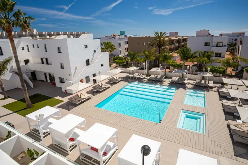 Vue aérienne d'une piscine entourée de transats blancs et d'une végétation luxuriante.