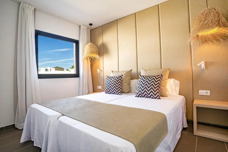 Une chambre lumineuse avec un grand lit et une décoration neutre.