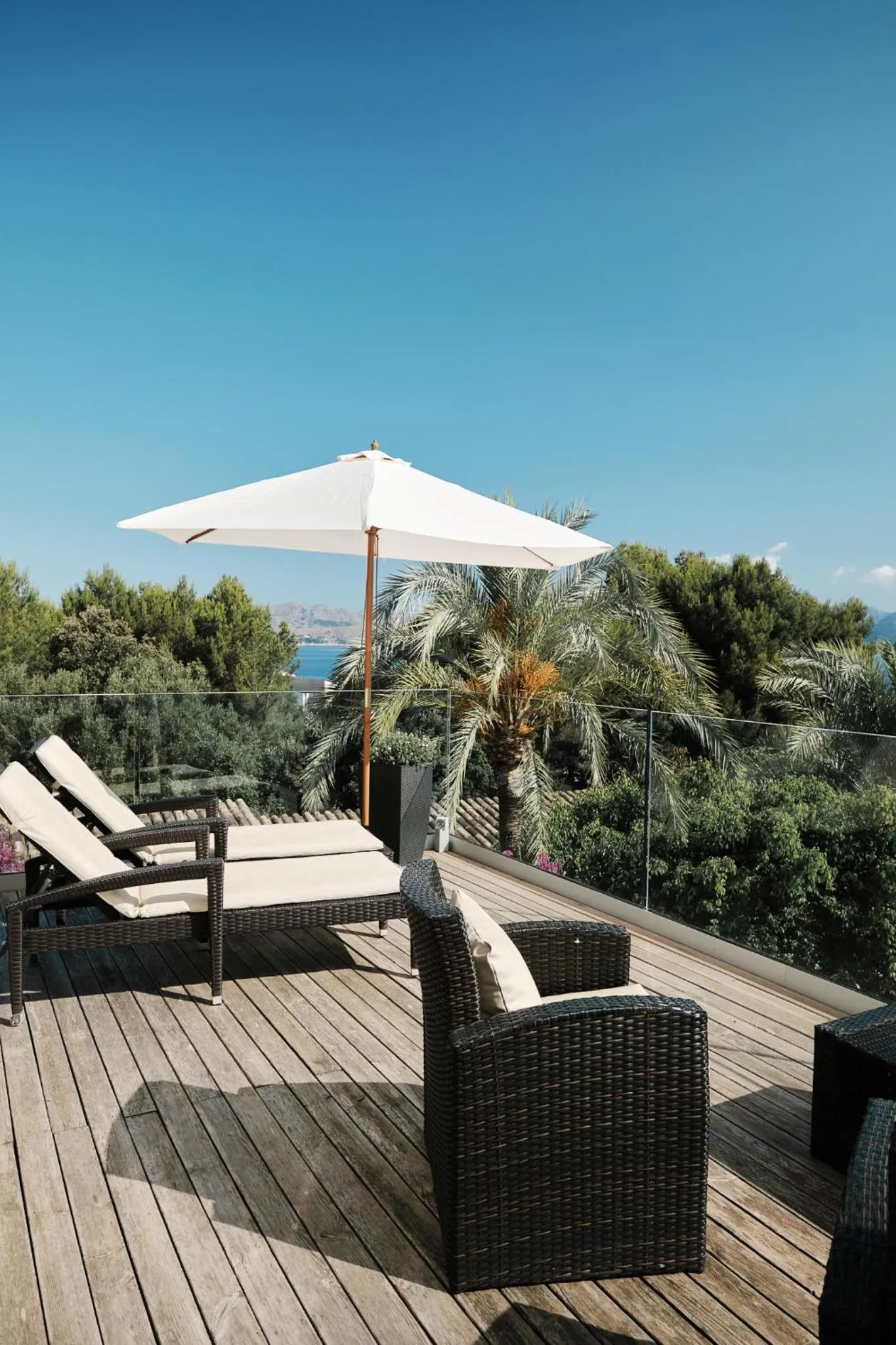 Terrasse aménagée avec chaises longues et mobilier de jardin face à la mer.