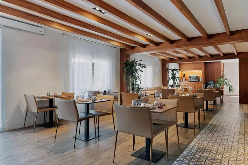 Une salle de restaurant lumineuse avec des tables dressées et des chaises claires.