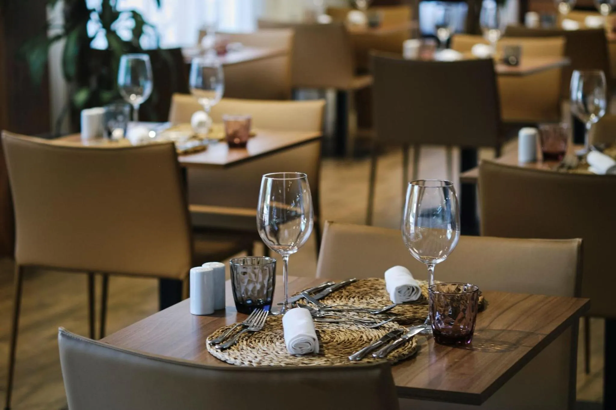 Une table de restaurant est dressée avec des couverts et des verres.