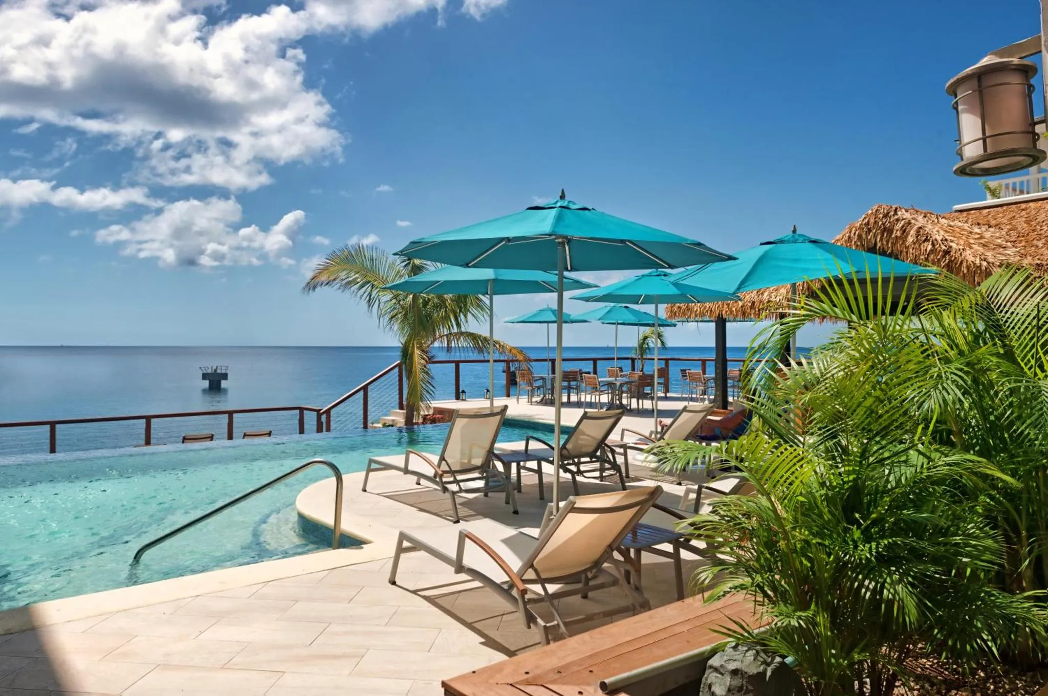 Terrasse avec transats et piscine à débordement surplombant la mer.
