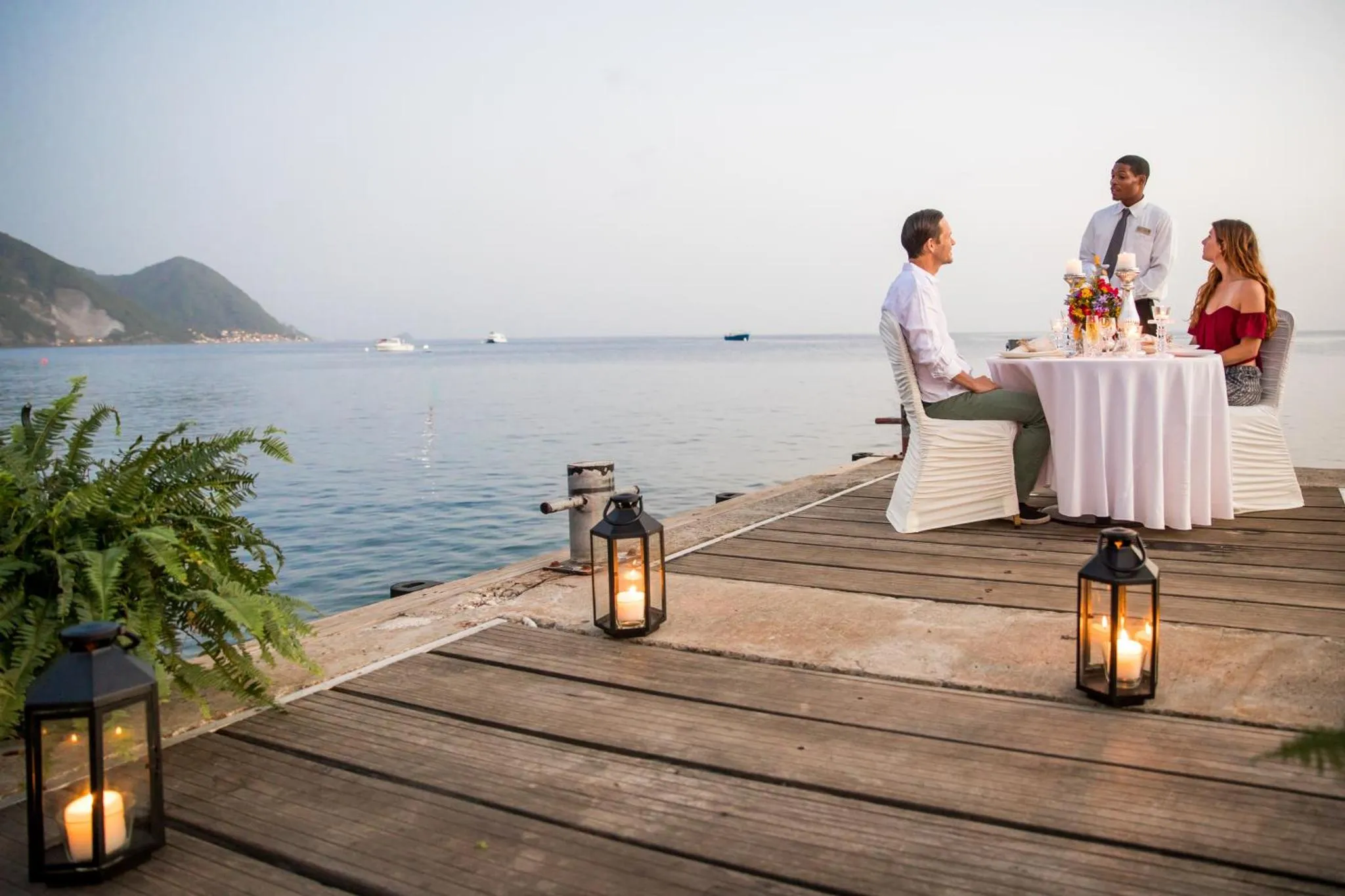 Un couple dîner sur une jetée en bois au coucher du soleil.
