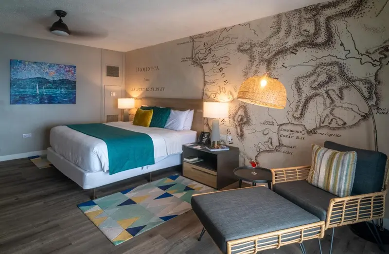 Une chambre à coucher lumineuse avec un lit fait et un coin salon.