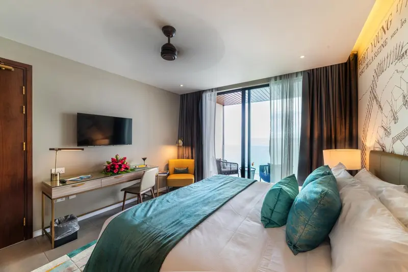 Une chambre lumineuse avec un lit recouvert d'une couverture turquoise et un bureau en bois.
