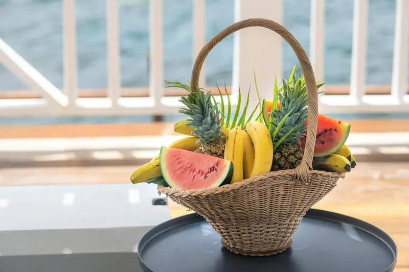 Un panier de fruits frais est présenté sur une table sombre.