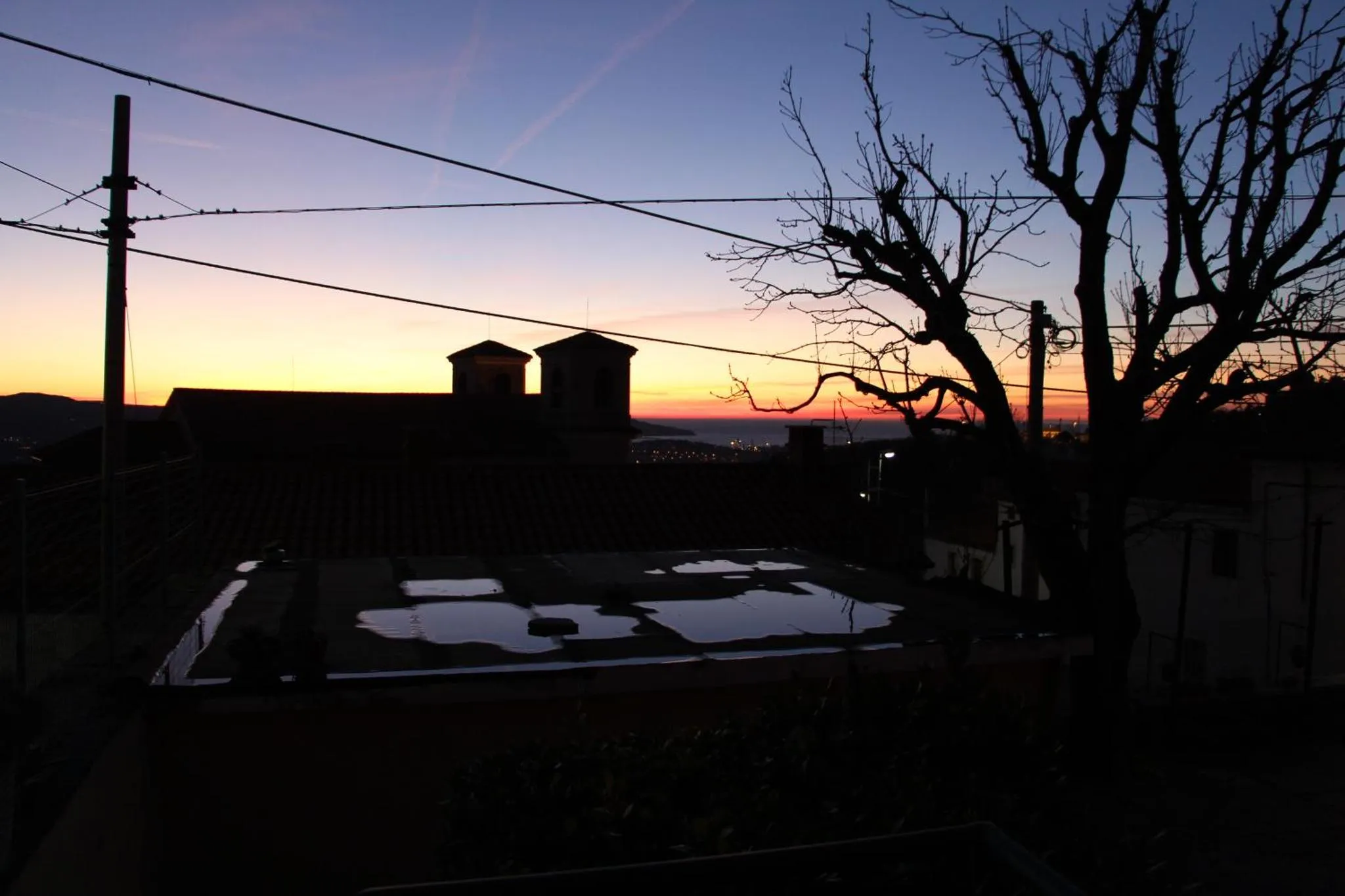 Silhouette d'un bâtiment au crépuscule avec une piscine sombre au premier plan.
