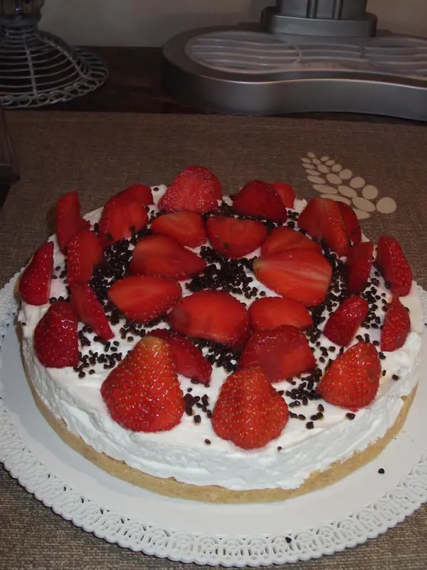 Un gâteau à la crème recouvert de fraises fraîches et de vermicelles en chocolat.
