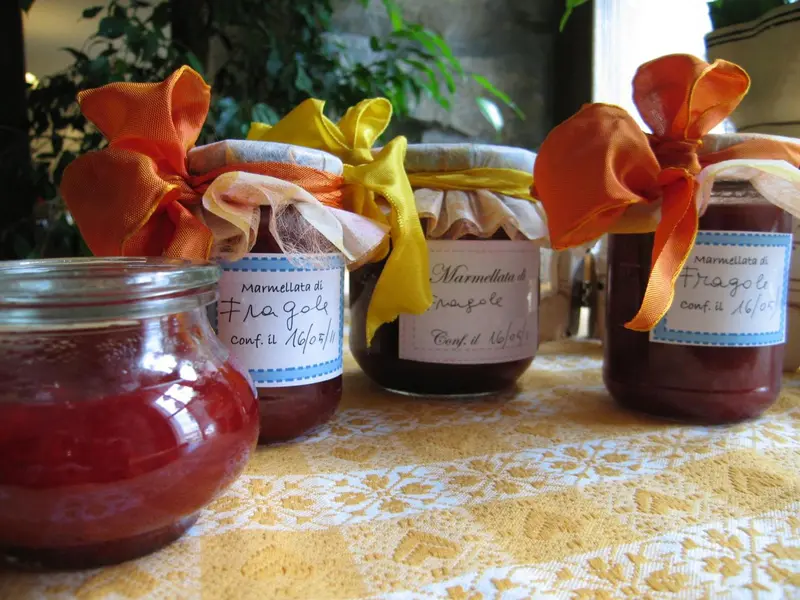 Des pots de confiture artisanale décorés de rubans colorés sont présentés sur une nappe.