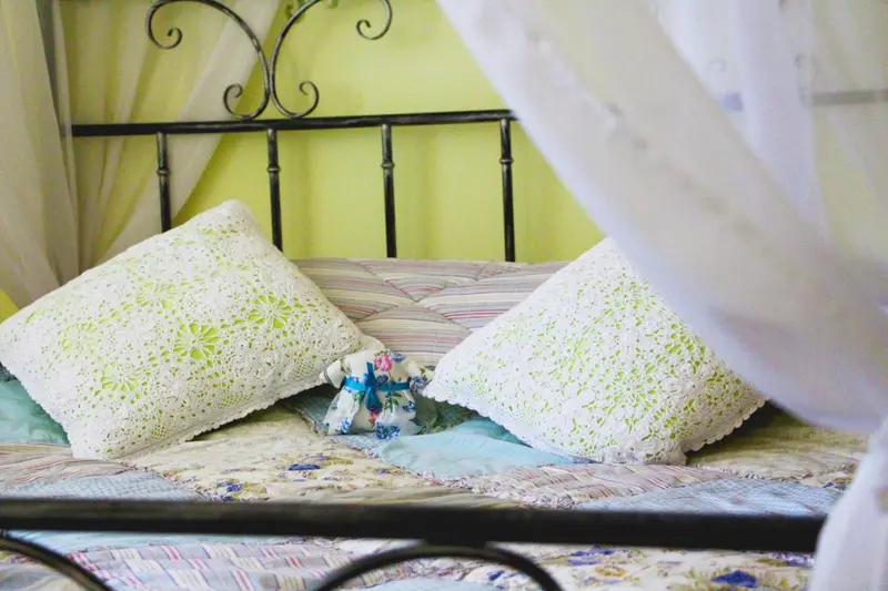 Un lit recouvert de textiles blancs et colorés, avec une moustiquaire.