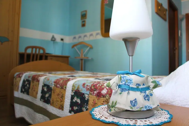 Une chambre lumineuse avec un lit recouvert d'une courtepointe colorée et une robe décorative sur une table de chevet.