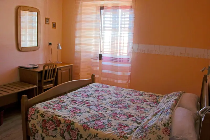 Une chambre lumineuse avec un lit recouvert d'une couette fleurie et un bureau en bois.