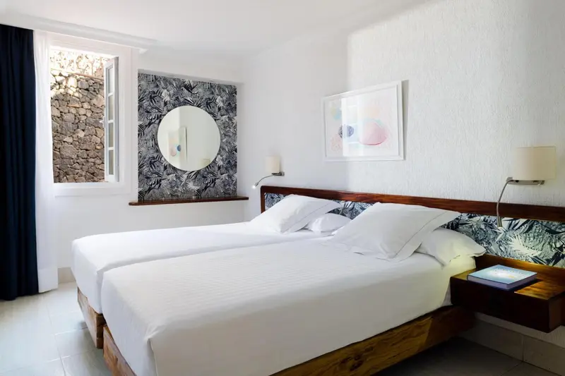 Une chambre lumineuse avec deux lits simples et une décoration murale.