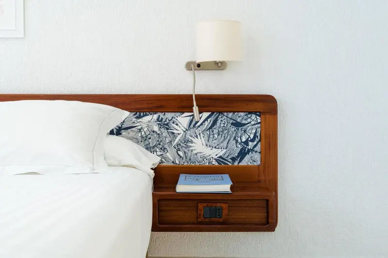 Un lit blanc avec une table de chevet en bois sombre.