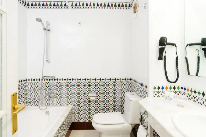 Une salle de bain lumineuse avec une baignoire et des motifs colorés sur les murs.