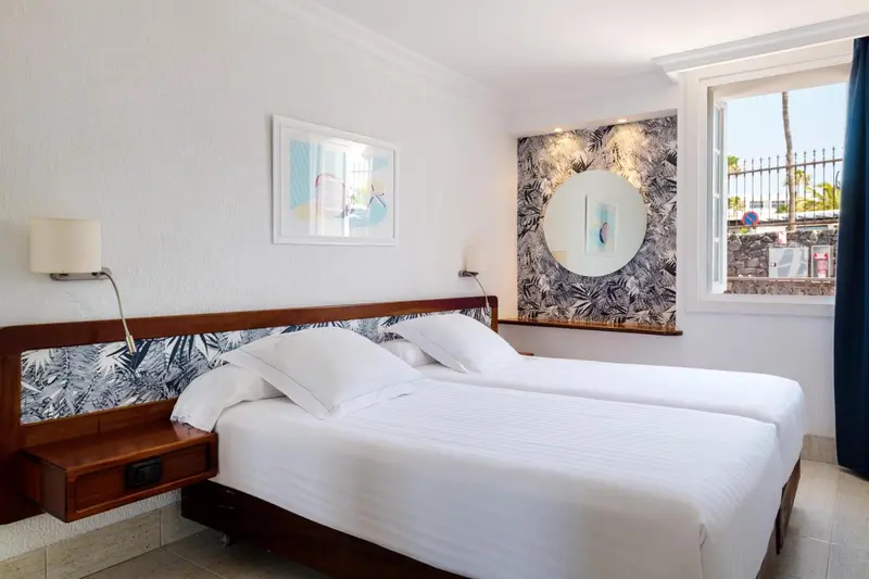 Une chambre lumineuse avec un grand lit et une décoration murale.