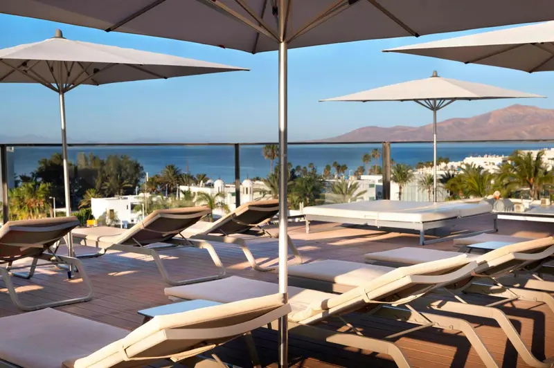 Terrasse aménagée avec transats et vue sur la mer.