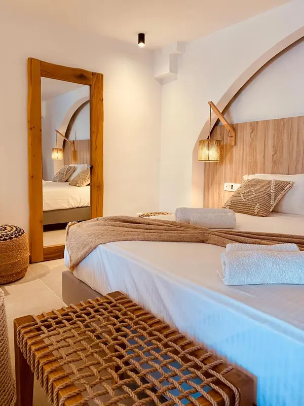 Une chambre lumineuse avec un grand lit et un miroir mural.