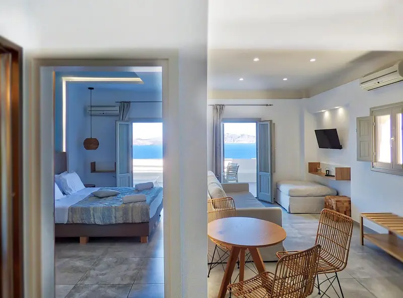 Une chambre lumineuse s'ouvre sur un espace salon avec vue sur la mer.
