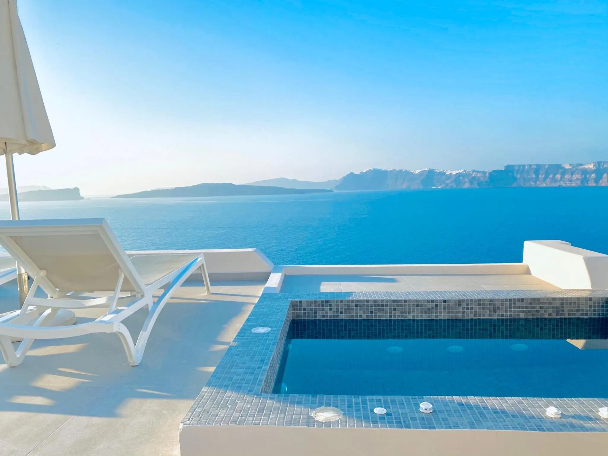 Terrasse avec transats et piscine à débordement donnant sur la mer.
