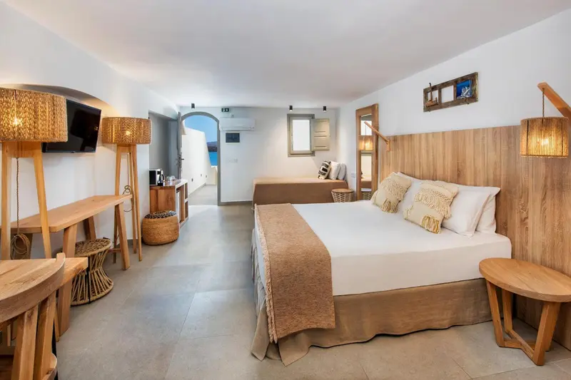 Une chambre lumineuse avec un grand lit et un bureau en bois.