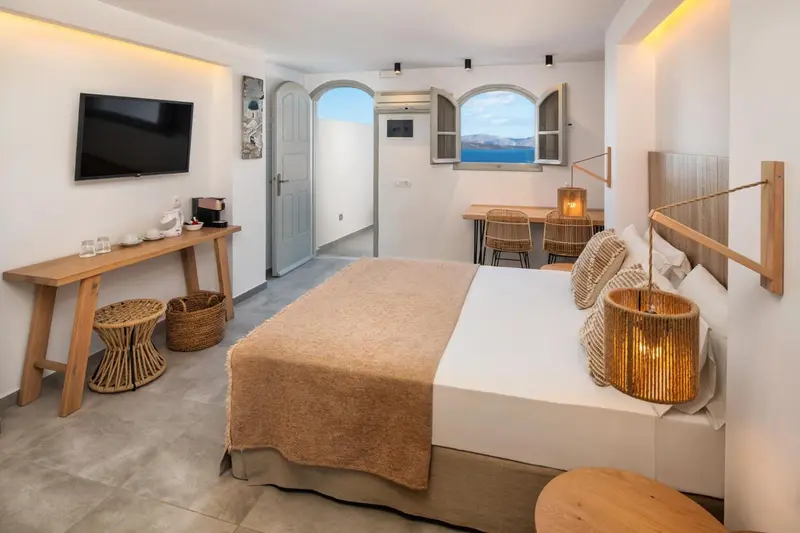 Une chambre lumineuse avec un lit double et un bureau donnant sur la mer.