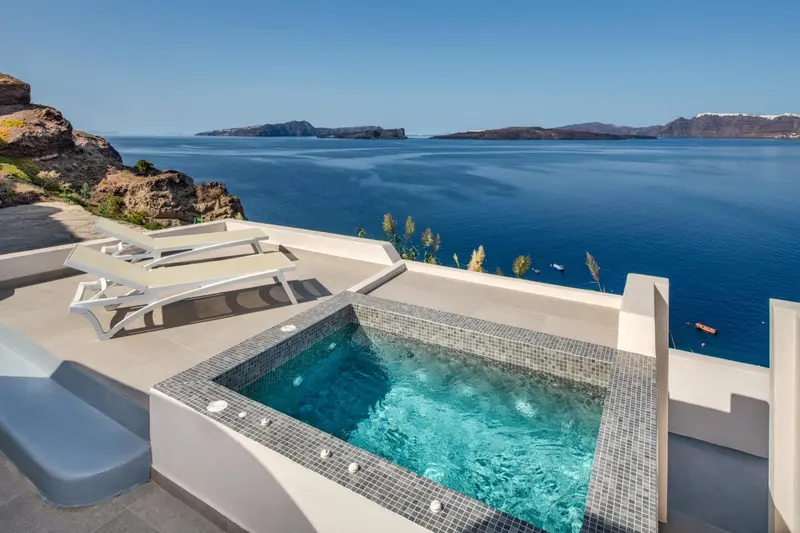 Jacuzzi sur terrasse avec vue sur la mer et le paysage rocheux.