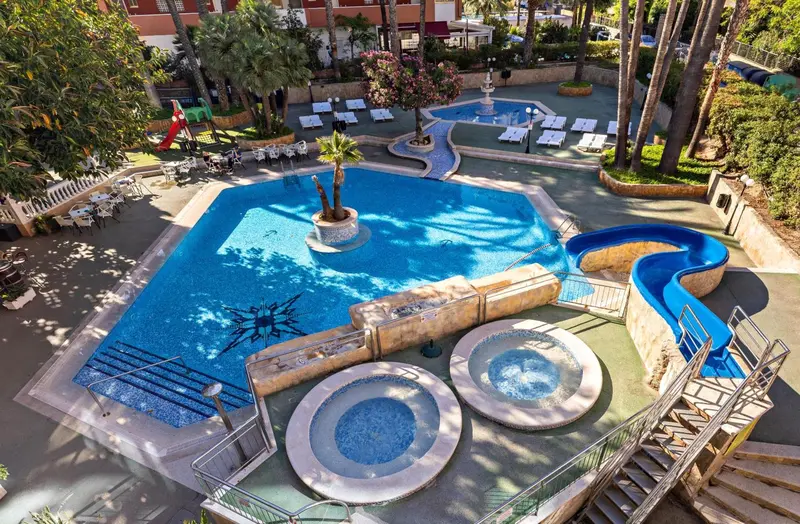 Vue aérienne d'une piscine d'hôtel avec toboggan et espaces de détente.
