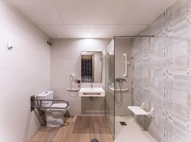 Une salle de bain moderne avec douche à l'italienne et équipements adaptés.