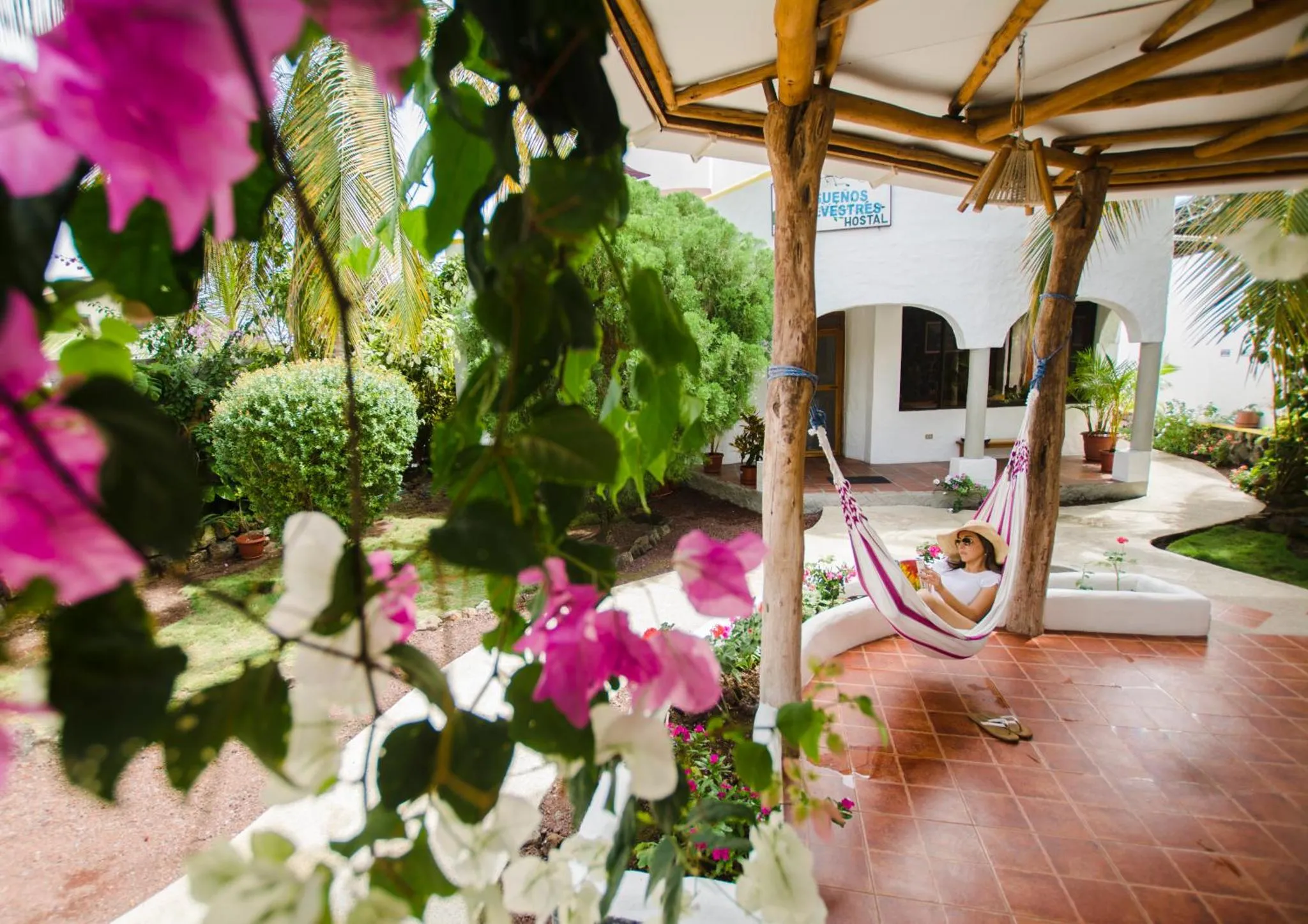Un hamac est suspendu sur une terrasse ombragée avec une végétation luxuriante.