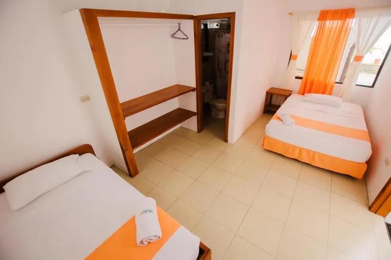 Une chambre lumineuse avec deux lits simples et un espace rangement.