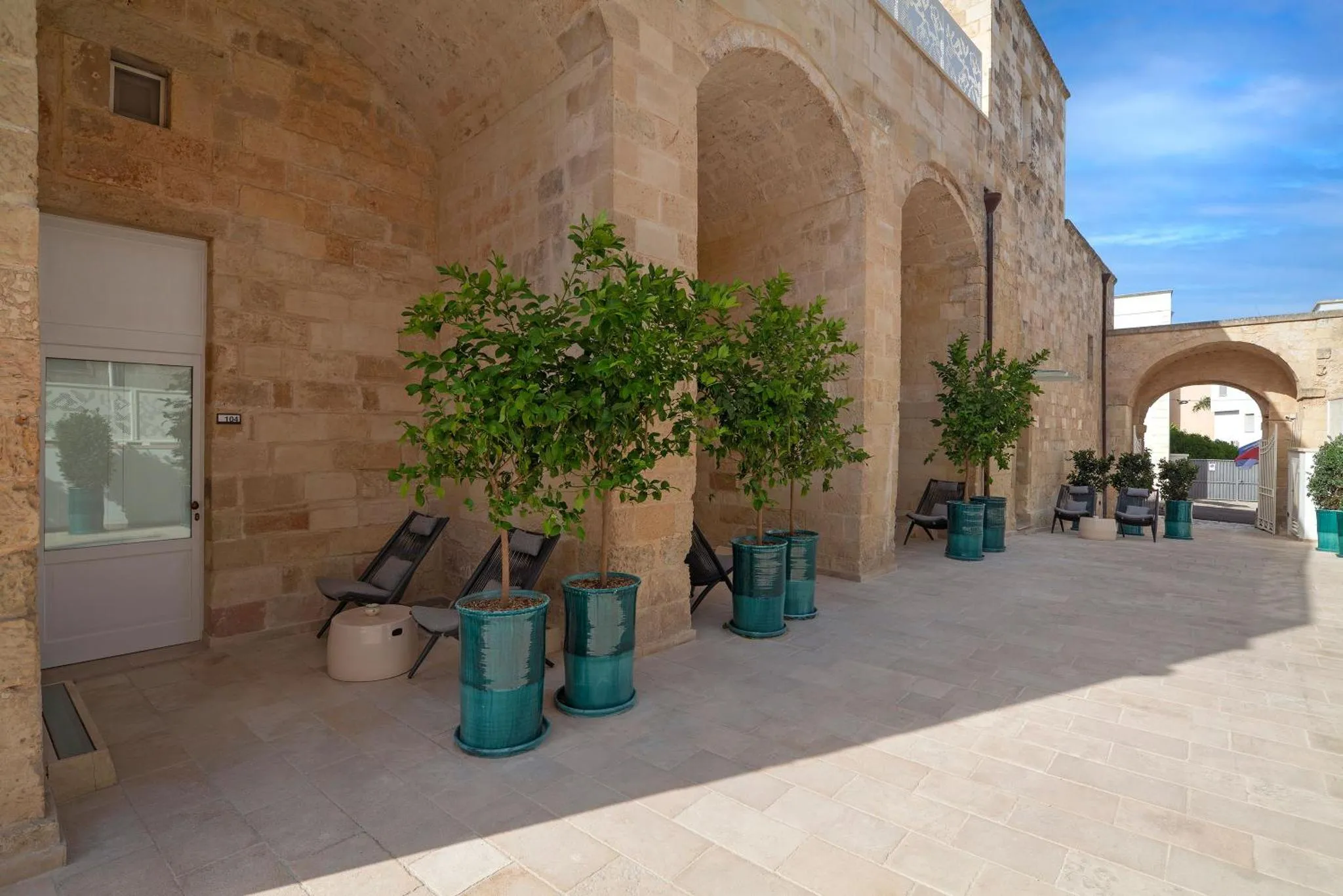 Terrasse ombragée avec des plantes en pot et des chaises longues.