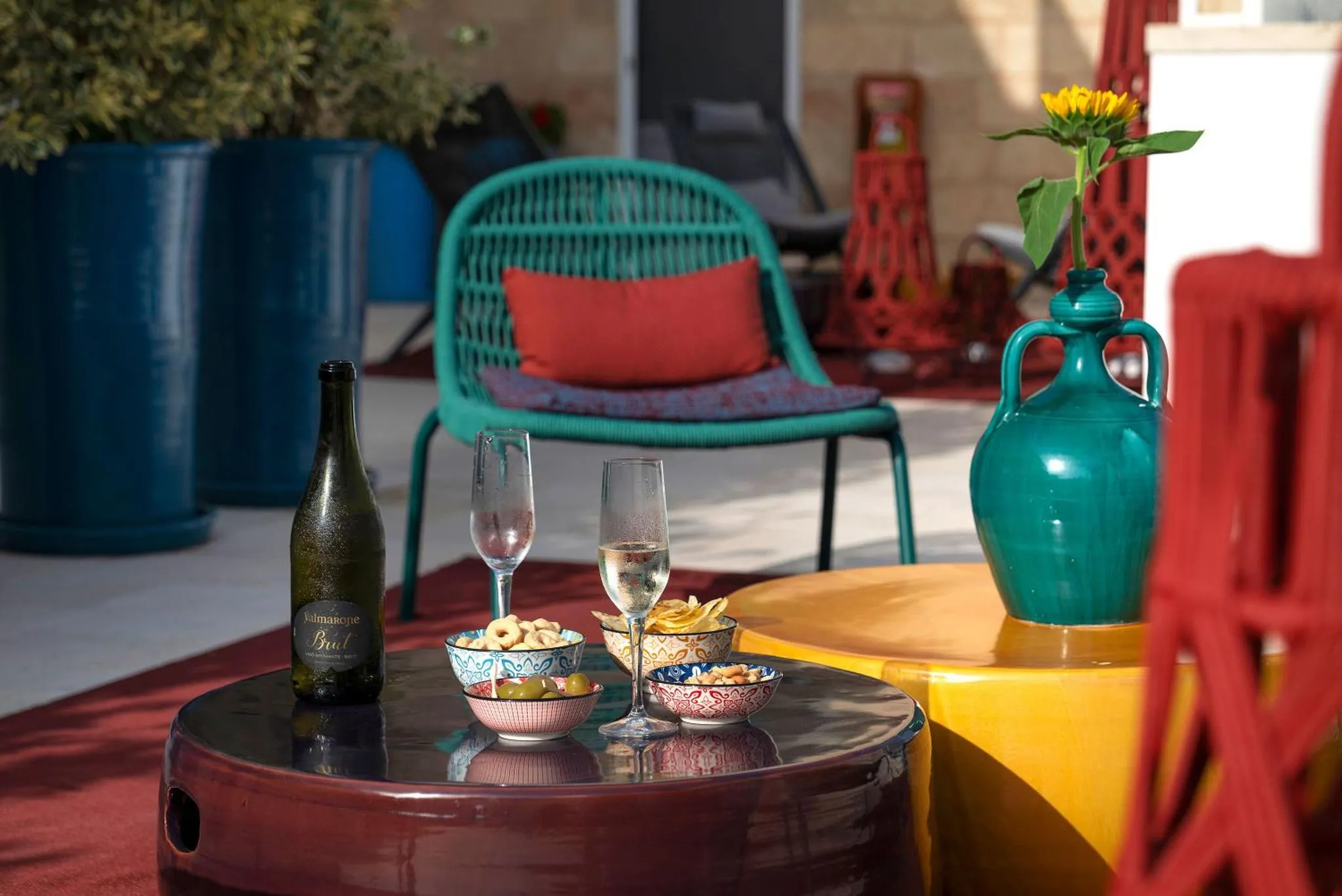 Une table basse avec des boissons et des amuse-gueules sur une terrasse ensoleillée.