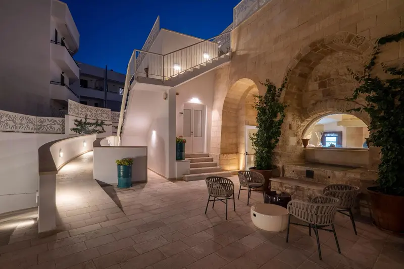 Terrasse pavée éclairée avec quelques meubles de jardin et un escalier en pierre.