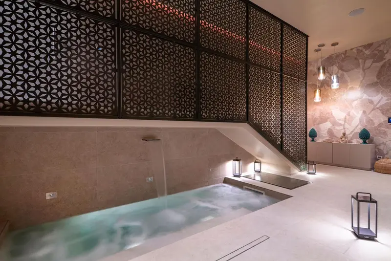 Un espace de relaxation intérieur avec un bain à remous et une décoration murale texturée.
