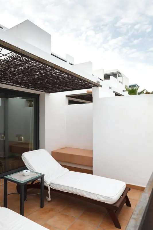 Transat blanc sur une terrasse carrelée ombragée.