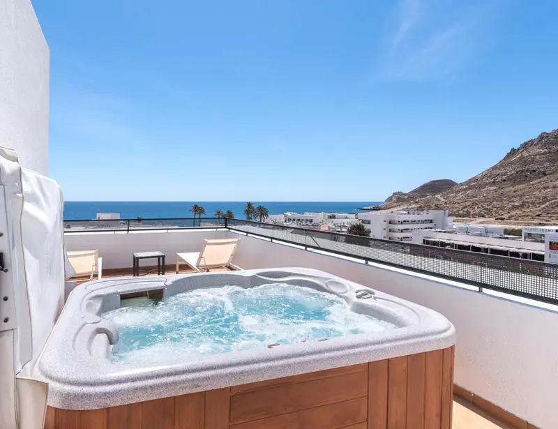 Jacuzzi sur une terrasse avec vue sur la mer et les montagnes.