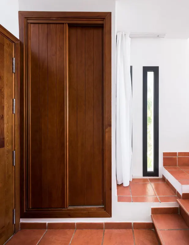 Une porte en bois est ouverte sur un intérieur clair et lumineux.