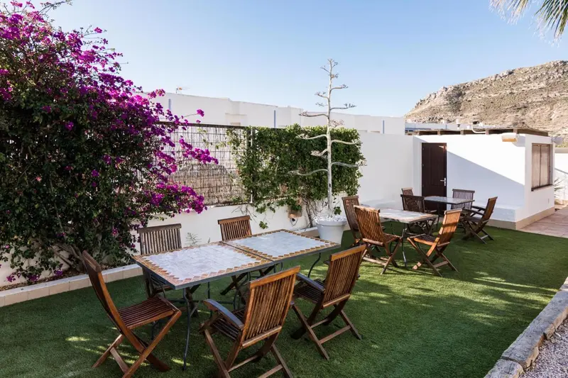 Tables et chaises disposées sur une terrasse en gazon synthétique, devant un mur végétal.