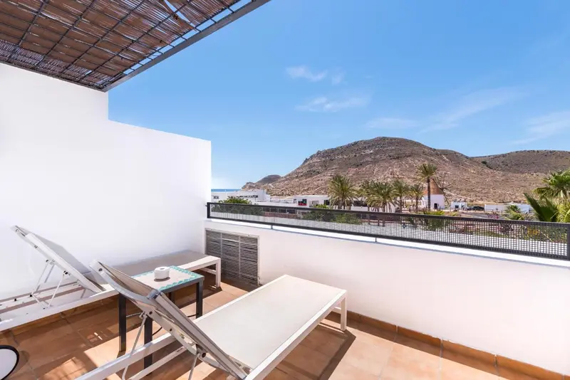 Terrasse avec transats et vue sur un paysage montagneux.