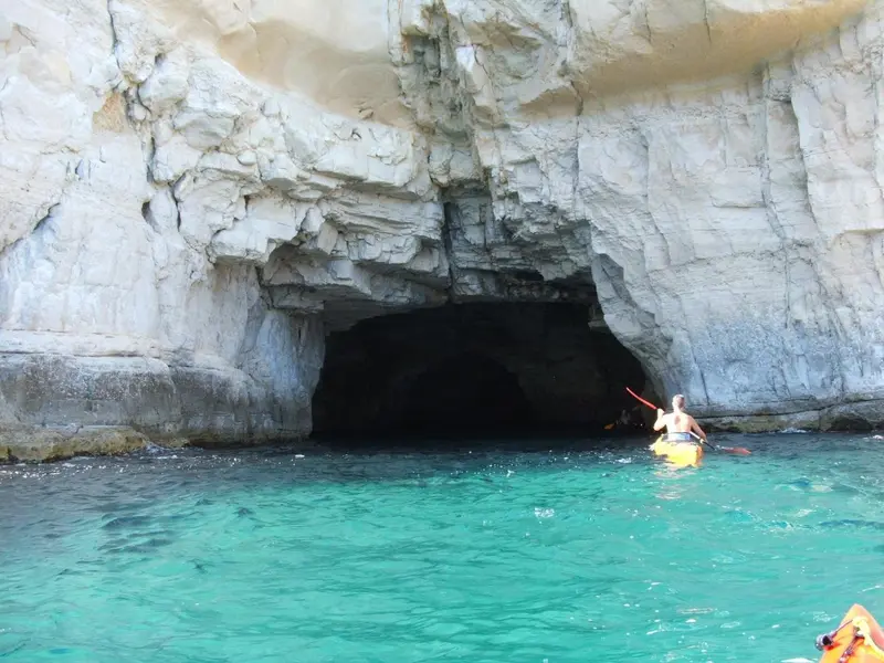 Une ouverture naturelle dans une falaise surplombe une eau turquoise.