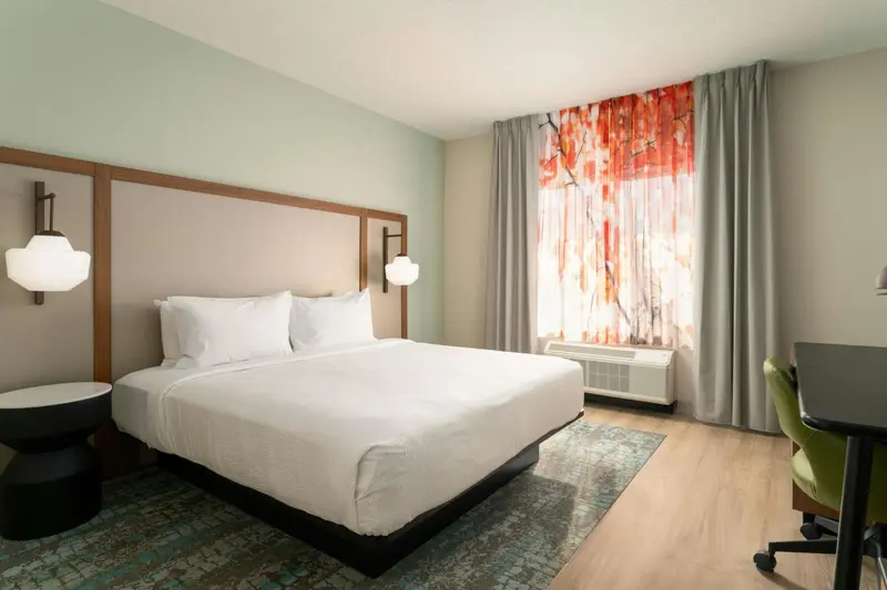 Une chambre d'hôtel lumineuse avec un grand lit et un bureau.