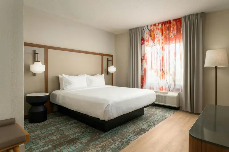Une chambre d'hôtel lumineuse avec un grand lit recouvert de draps blancs.