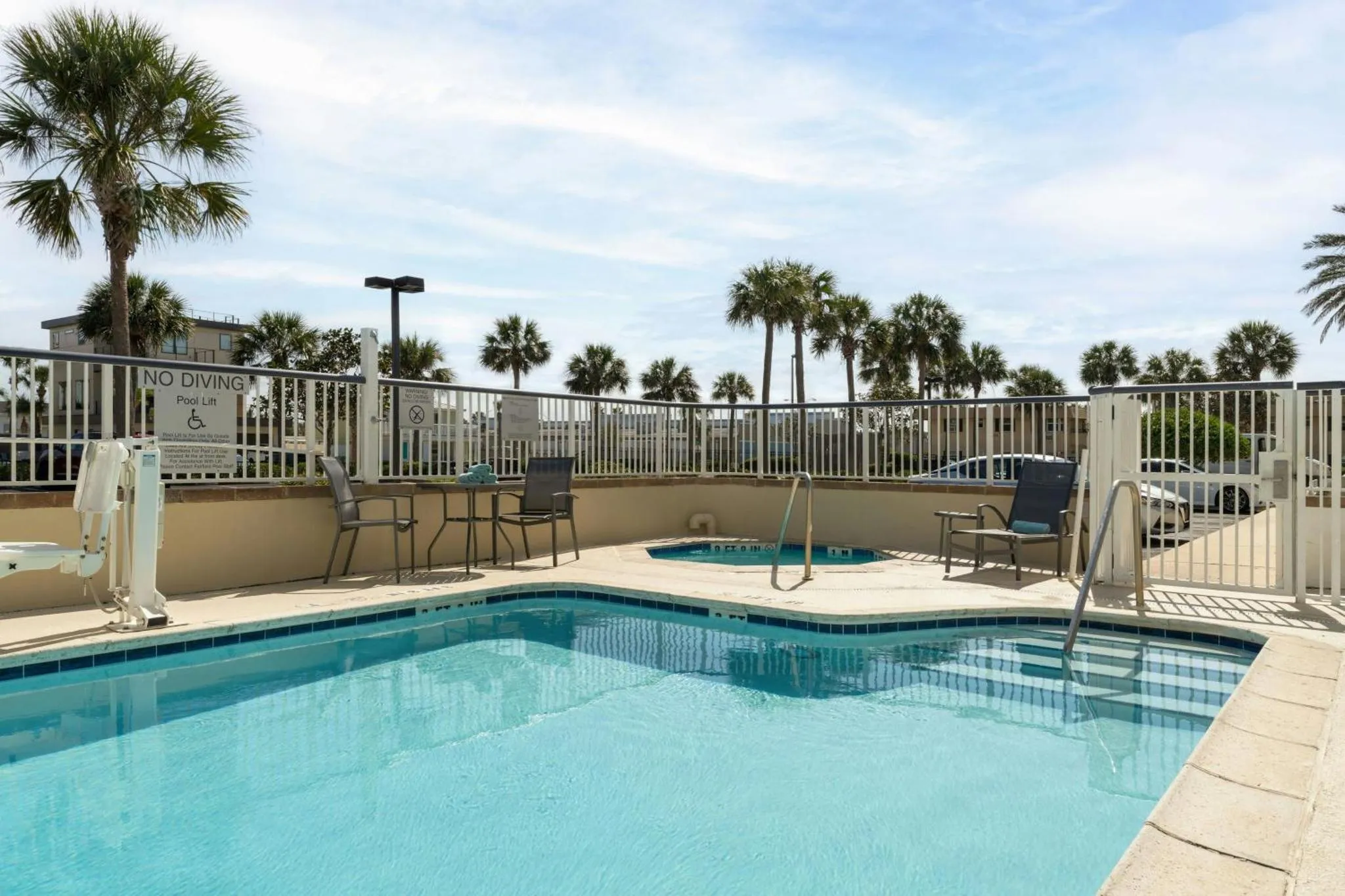 Une piscine turquoise avec des chaises longues et des palmiers en arrière-plan.