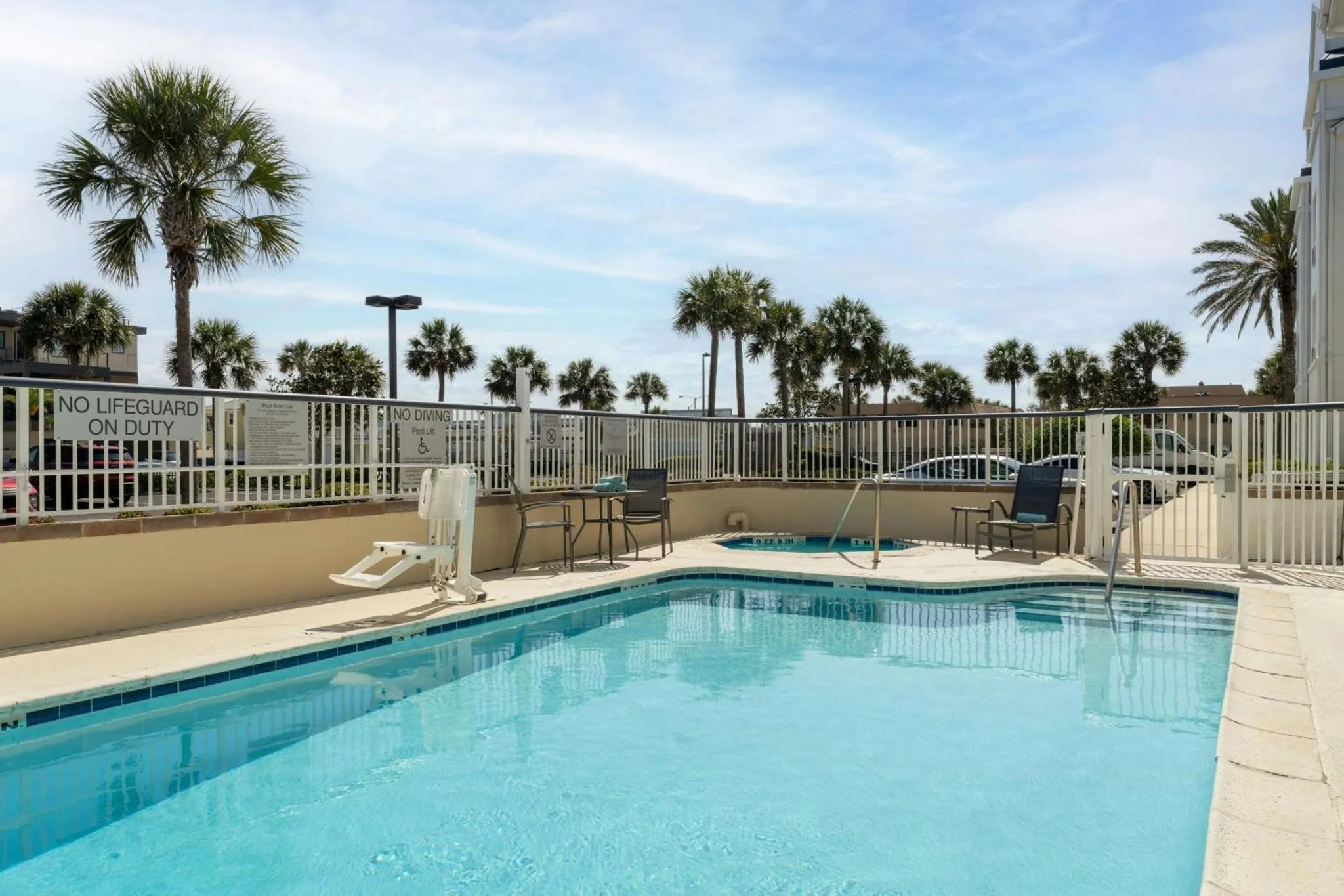 Une piscine rectangulaire avec des transats et des palmiers en arrière-plan.