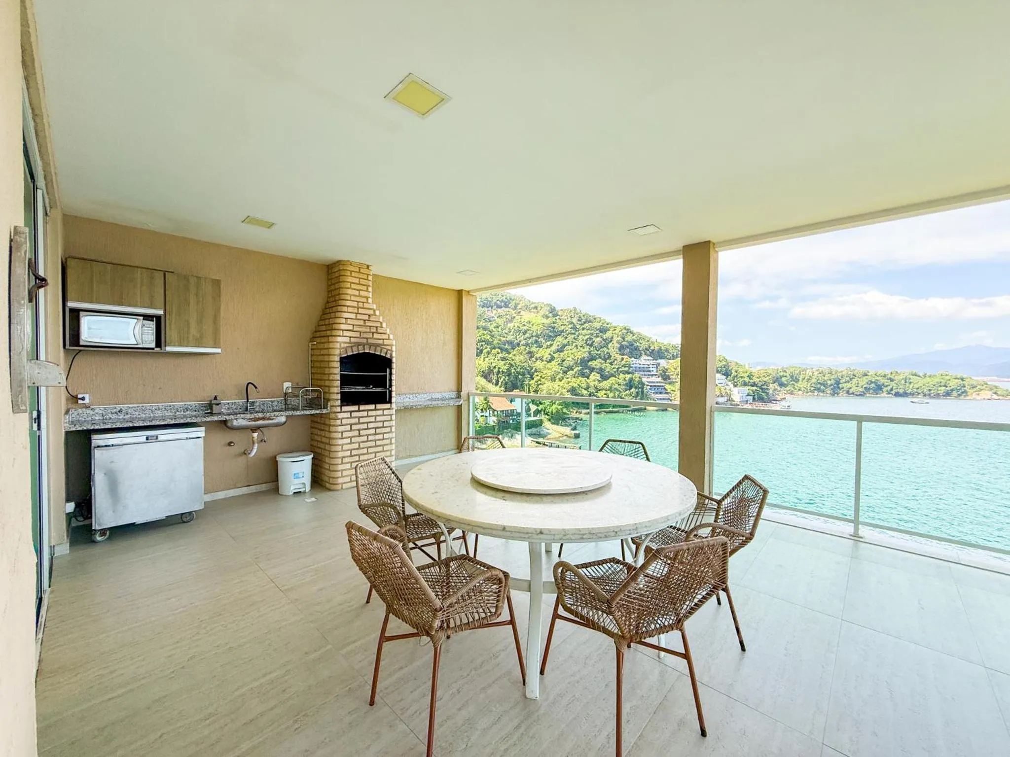 Espace extérieur aménagé avec un coin cuisine et une table ronde face à la mer.