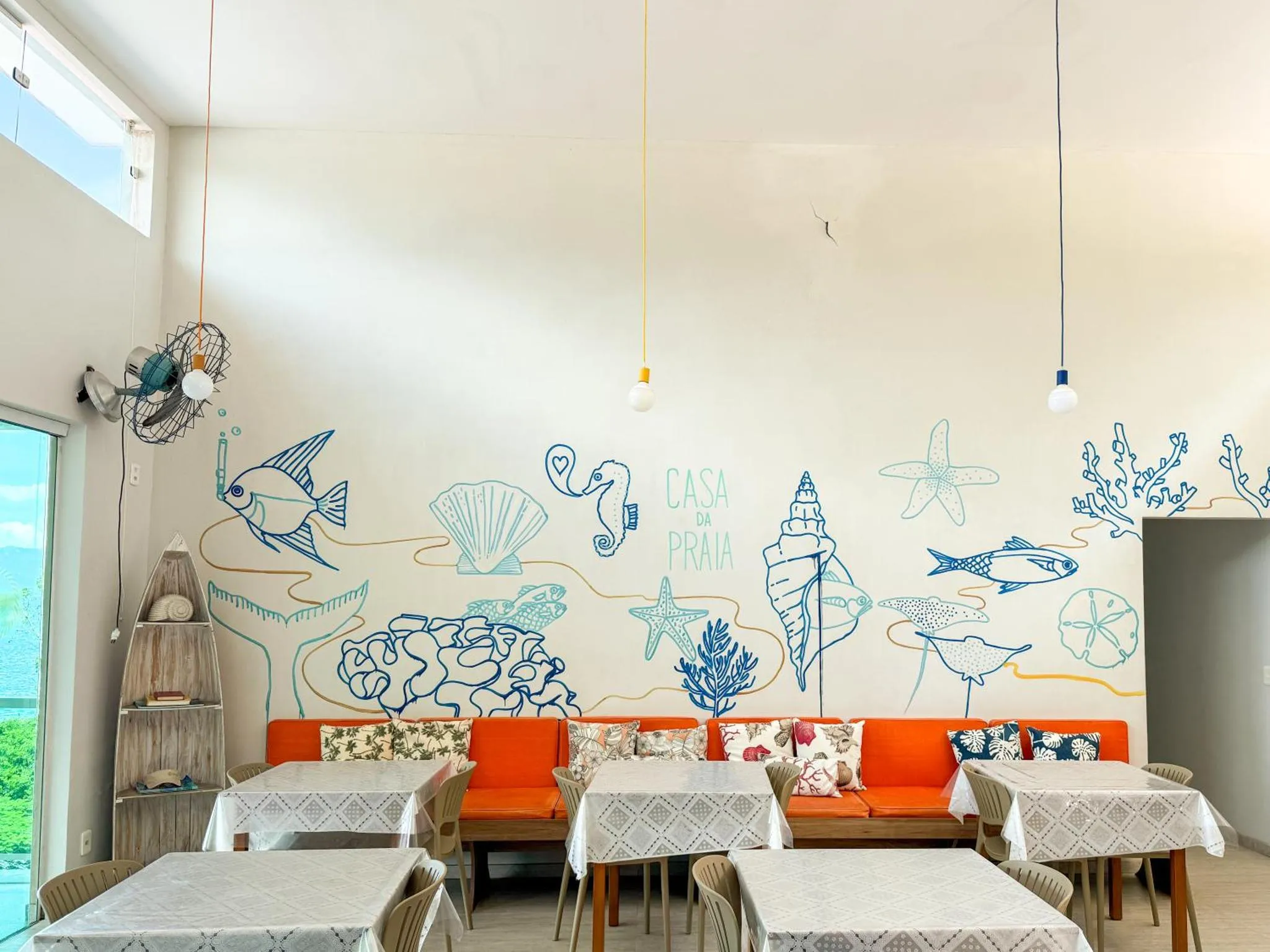 Une salle de restaurant décorée de motifs marins avec des tables et des banquettes.