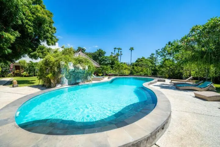 Une piscine turquoise bordée d'une terrasse ensoleillée.