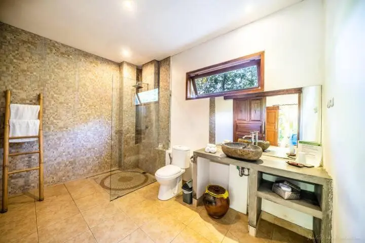 Une salle de bain lumineuse avec douche à l'italienne et vasque en pierre.